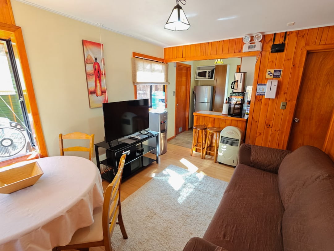 Living and dining area of the Elite Bungalow with TV, equipped kitchen and bamboo floors