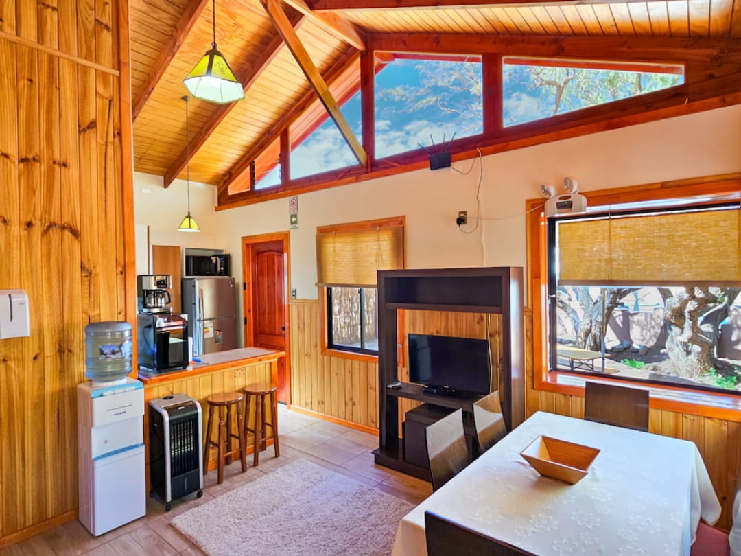 Living and dining area of the Superior Bungalow with high wooden ceiling, TV and equipped kitchen